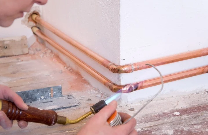 Person lötet Kupferrohre